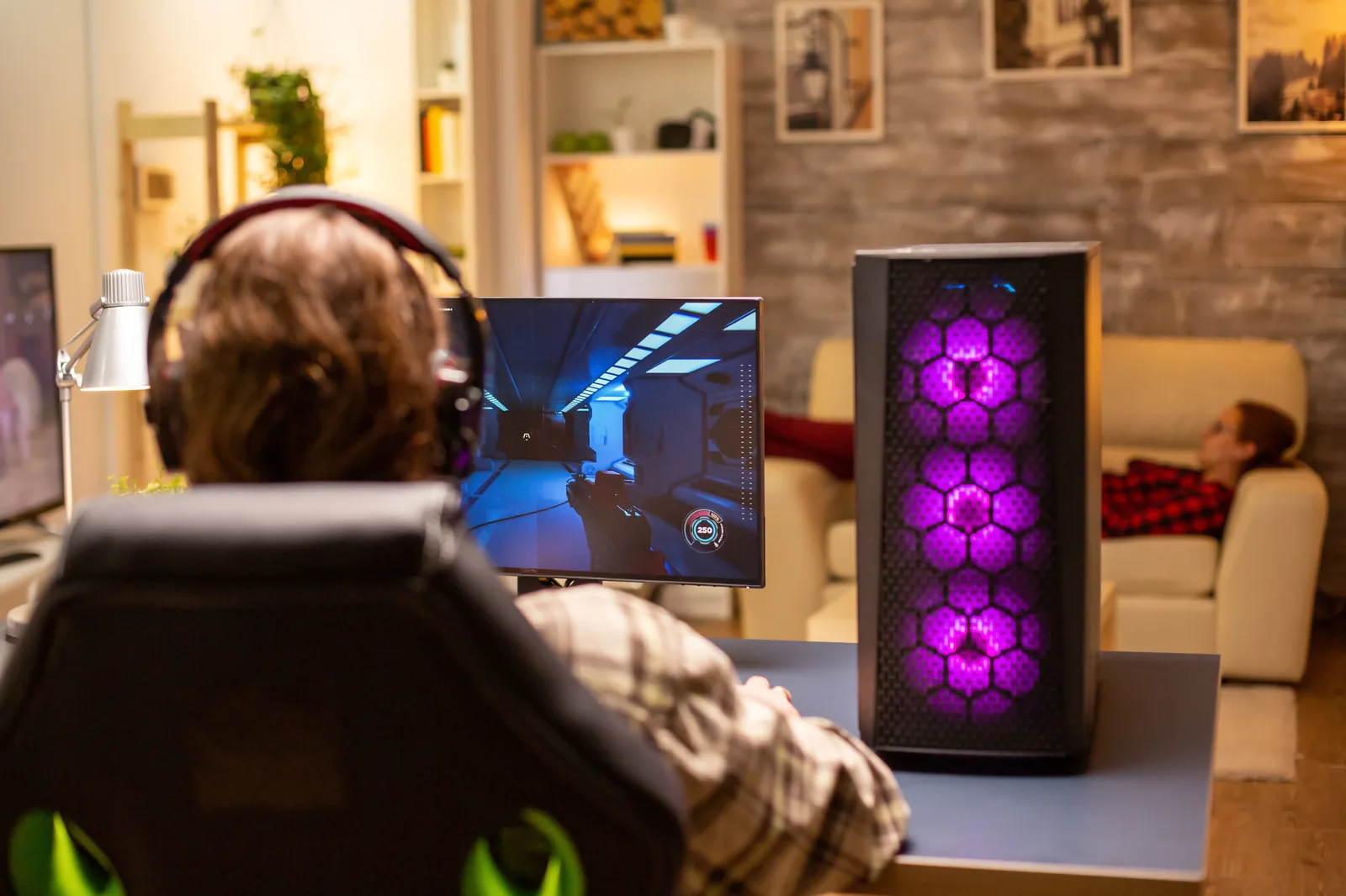 Gaming-PC mit lila beleuchtetem Gehäuse neben einem Monitor